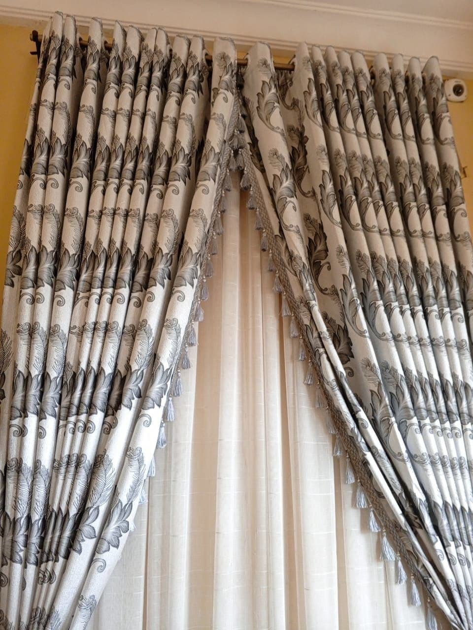 Patterned curtains with tasselled tiebacks drawn back over sheers