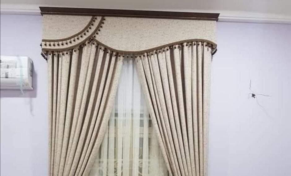 Curtains hung beneath a shaped pelmet with a sheer behind