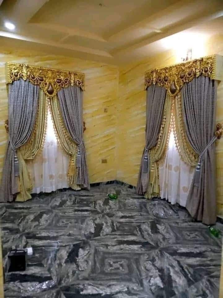 Layered curtains beneath ornate gold pelmets on two windows