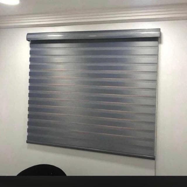 Grey woven day & night blind fitted above a skirting-level wall